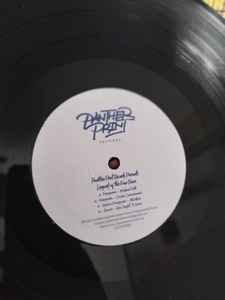 Close-up of a vinyl record with a white center label featuring stylized text and track list.