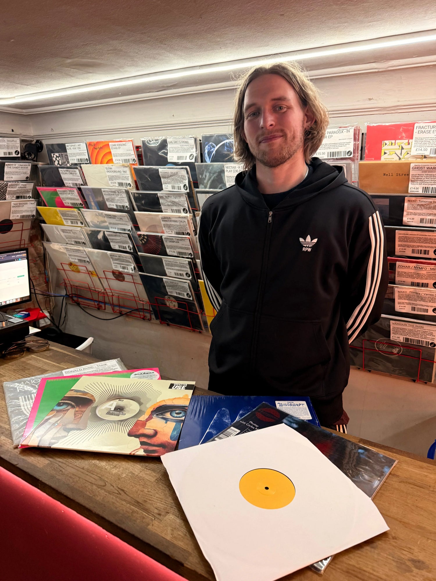 Man standing behind record store counter with vinyl records and album covers on display