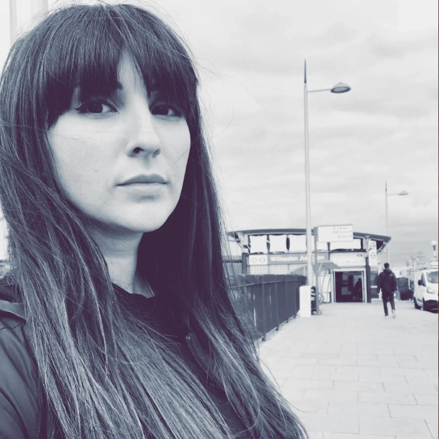 Woman with straight hair in black and white outside Willesden Junction station