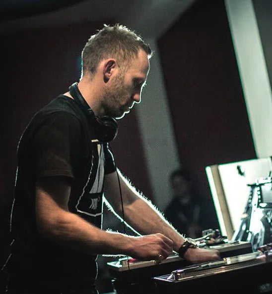 DJ mixing vinyl records on turntable in dimly lit music studio