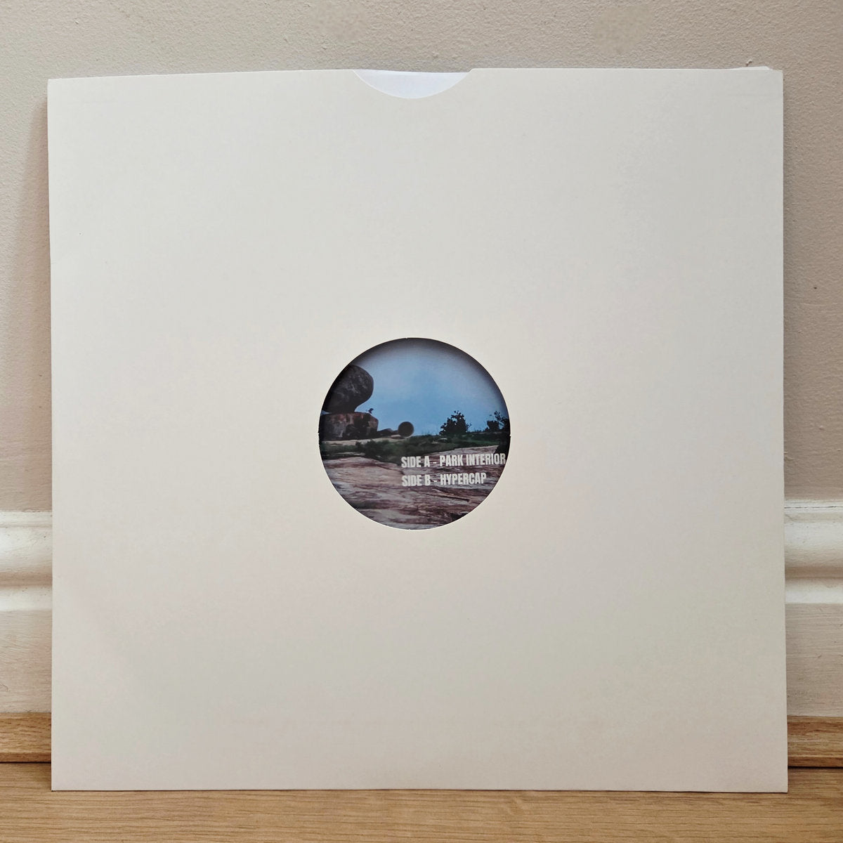 Vinyl record in plain white sleeve showing label with park landscape and text Side A Park Interior Side B Hypercap