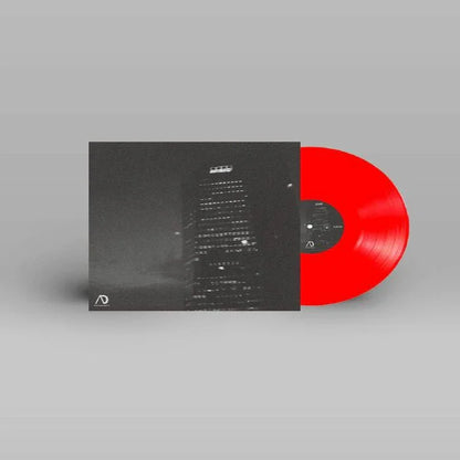 Red vinyl record with black and white city skyscraper cover art on a grey background