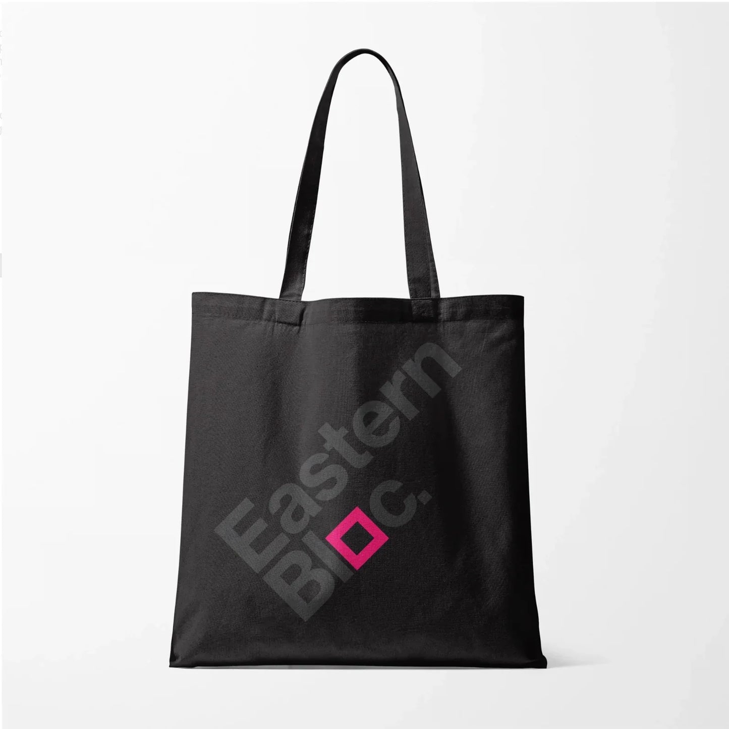 Black tote bag with diagonal grey 'Eastern Bloc.' text and pink square design on white background