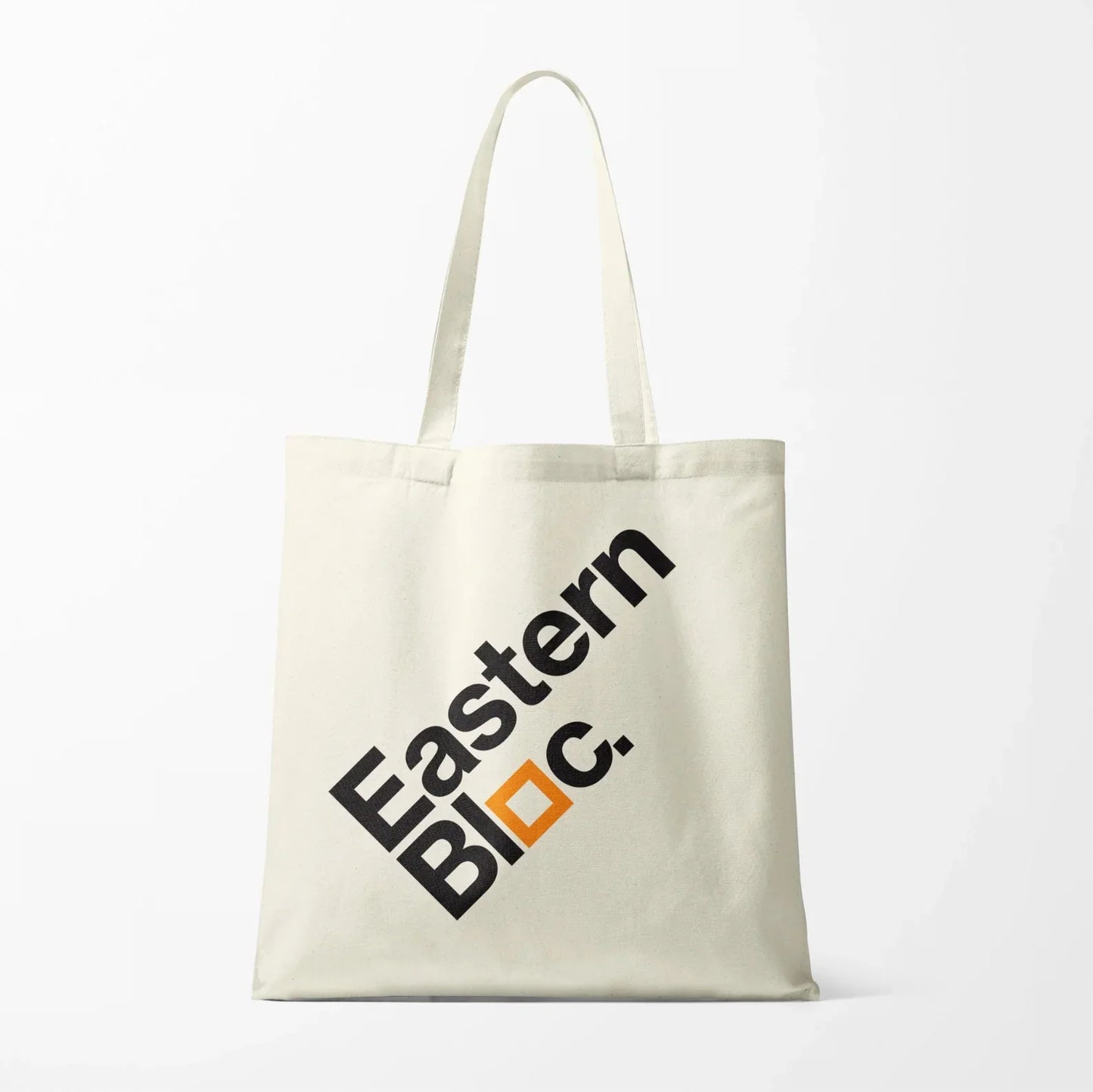 Cream tote bag with black 'Eastern Bloc.' text and orange square accent, plain background